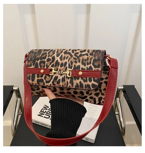 Close-up of leopard print shoulder bag with red leather trim and gold horsebit hardware