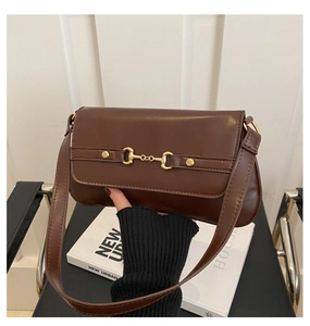 Detail of vintage brown leather underarm bag featuring a gold horsebit buckle and slim strap