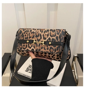 Detail of trendy leopard print underarm bag with gold horsebit buckle on a white book
