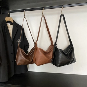 Sacs cabas en cuir souple marron et noir suspendus dans un dressing minimaliste