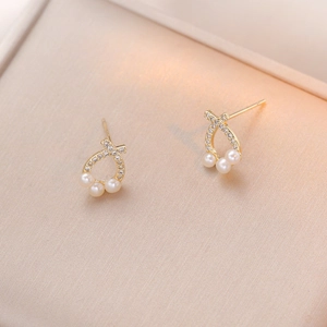 Elegant gold freshwater pearl earrings with diamond knots on champagne satin gift box
