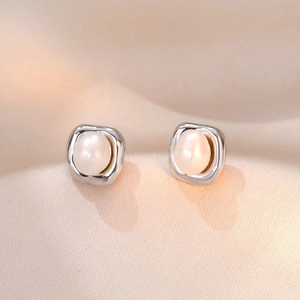 Minimalist irregular square silver earrings with elegant white pearls on silk background