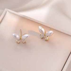 Elegant butterfly stud earrings with pearl wings and zircon drops on golden display stand