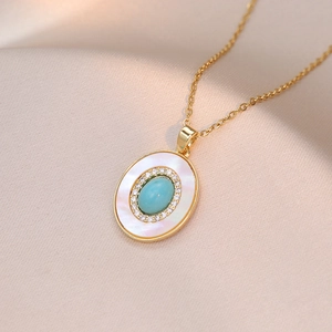 Collier doré avec pendentif ovale en turquoise et zircon sur fond de soie champagne