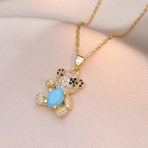 Golden bear necklace with sparkling zircons and blue stone on champagne silk background