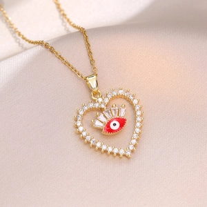 Gold heart evil eye necklace with colorful zircon and red eye on champagne satin