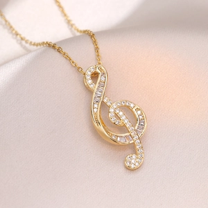 Golden musical note pendant necklace with sparkling white zircons on soft satin