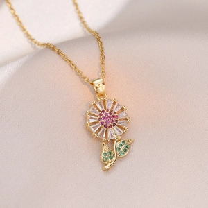 Collier tournesol doré orné de zircons roses et verts sur fond de satin champagne