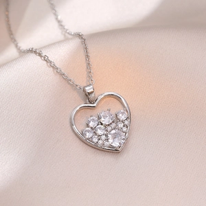 Elegante collana con ciondolo a cuore in argento e zirconi su sfondo di seta color champagne