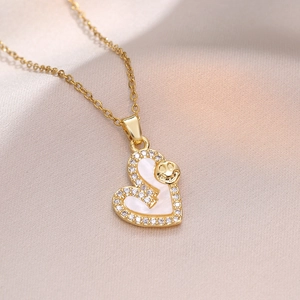 Collier coeur doré avec incrustation de nacre et zircon sur un fond en soie blanche
