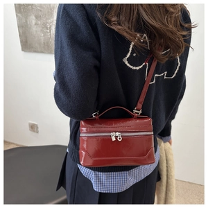 Close-up of deep red patent leather box bag with silver hardware and top handle strap