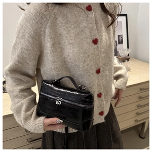 Detail of elegant black glossy box bag with silver zippers and stylish handle