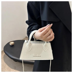 Close-up of white croc-embossed trapezoid handbag with FASHION & BAGS branding