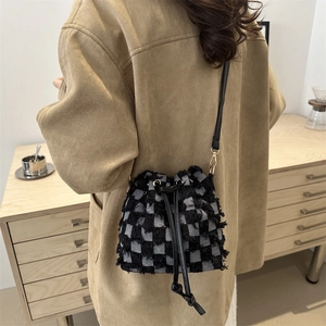 Fringed black and white checkered denim bucket bag with leather shoulder strap