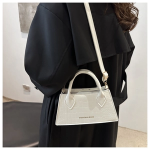 Detail of white crocodile pattern handbag with FASHION & BAGS logo on black coat