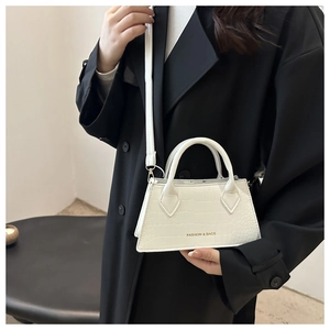 Detail of white crocodile pattern shoulder bag with golden text and slim leather strap