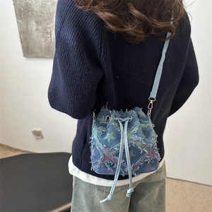 Fringe denim bucket bag with colorful star prints and drawstring strap on model