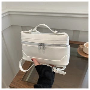 Detail of white leather box bag featuring silver dual zippers and comfortable top handle