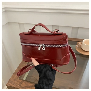 Detail of burgundy box bag featuring glossy faux leather and silver zipper hardware