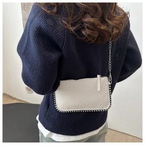 Detail of white animal-patterned crossbody bag with silver bead trim and chain strap