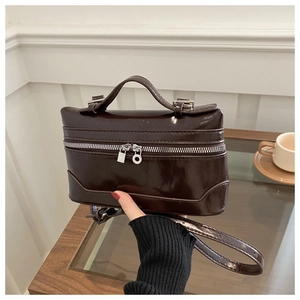 Detail of dark brown glossy leather box bag with silver zipper and vintage lock puller