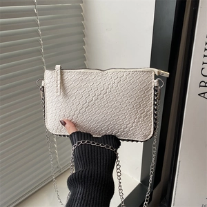 Detail of white woven texture crossbody bag with silver chain and side rivets