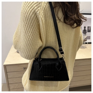 Detail of black crocodile texture handbag with gold lettering and adjustable strap