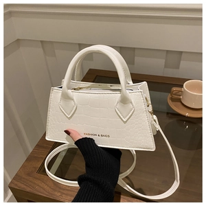 Close-up of white crocodile pattern PU handbag featuring gold-tone metal hardware and strap