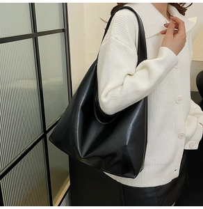 Vue latérale d'un grand sac cabas noir en cuir brillant porté par un mannequin