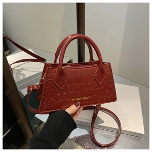 Close-up of burgundy crocodile pattern crossbody bag with golden metal lettering