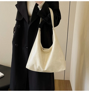 Grand sac hobo minimaliste crème sur un modèle portant un trench-coat noir élégant