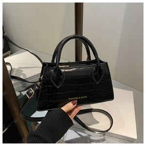Detail of black crocodile pattern crossbody bag with dual handles and metal zipper closure