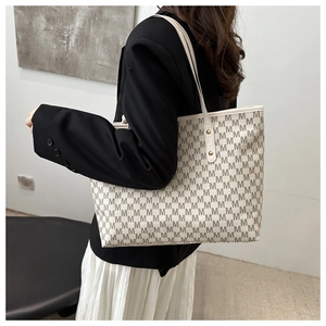 Detail of vintage beige tote bag with M letter print and slim shoulder straps on model
