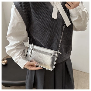 Close-up of metallic silver crossbody bag with rivet details and elegant chain strap