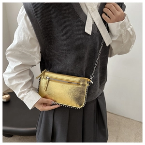 Close-up of gold metallic crossbody bag with silver studs and a vintage chain strap