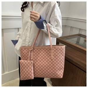 Detail of pink tote bag with M-letter pattern, golden rivets and matching pouch