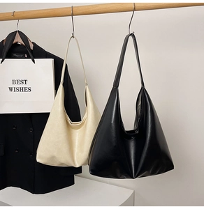 Detail view of large minimalist black and beige tote bags hanging on a wooden rod
