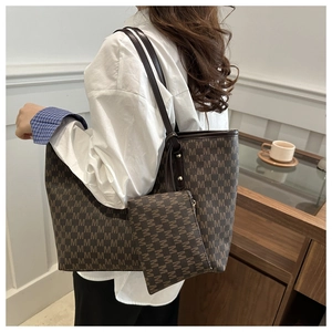 Detail of a deep brown printed tote bag and pouch set on a model in a cozy indoor setting