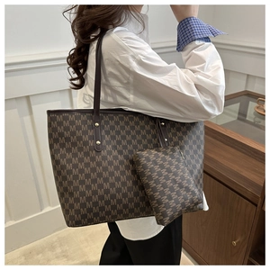 Detail of vintage tote bag set with monogram print and gold hardware shown on shoulder