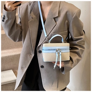 Detail of canvas box bag with blue leather trim and long tassel zipper pulls