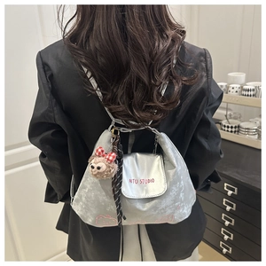 Detailansicht des silbernen Metall-Rucksacks mit AITU STUDIO Text und Plüsch-Anhänger