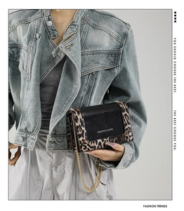 Detail of crossbody bag featuring leopard print trim and golden chain strap