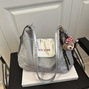 Detail einer silbernen Metallic-Tasche mit süßer Bärenstickerei und Markenlogo
