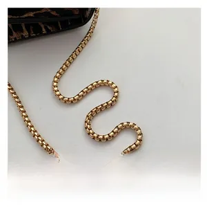 Detail of a bright golden box chain shoulder strap on a stylish leopard print handbag