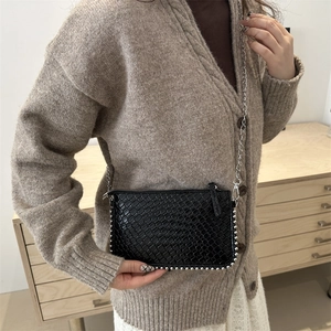 Minimalist black woven chain crossbody bag with silver studs and metal strap shown on model