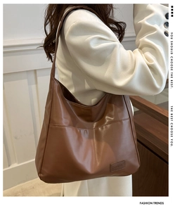 Détail d'un grand cabas en cuir PU souple marron porté avec un blazer blanc élégant