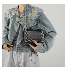 Detail of leopard print flap bag with gold chain strap and metal fashion logo