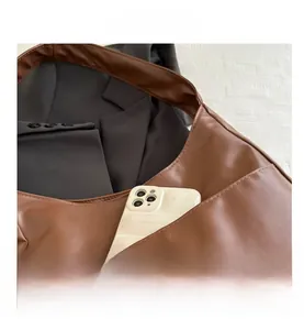 Détail du sac hobo en cuir PU marron avec poche avant et texture douce et lisse