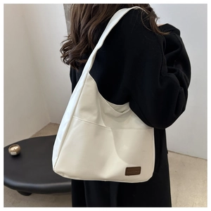 Détail du sac cabas blanc cassé avec une étiquette en cuir et une poche latérale utile