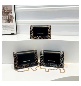 Three leopard print crossbody bags with golden chain straps on white tiered steps